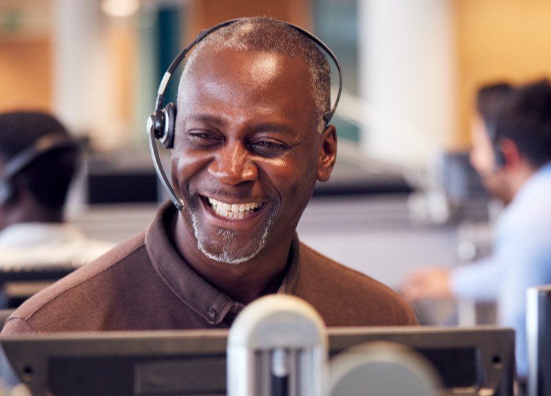 Man wearing headset while sitting at a computer talking about population health management. 