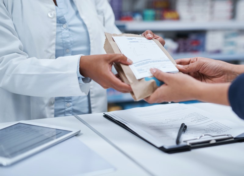 Pharmacist handing a patient their prescription in a bag.