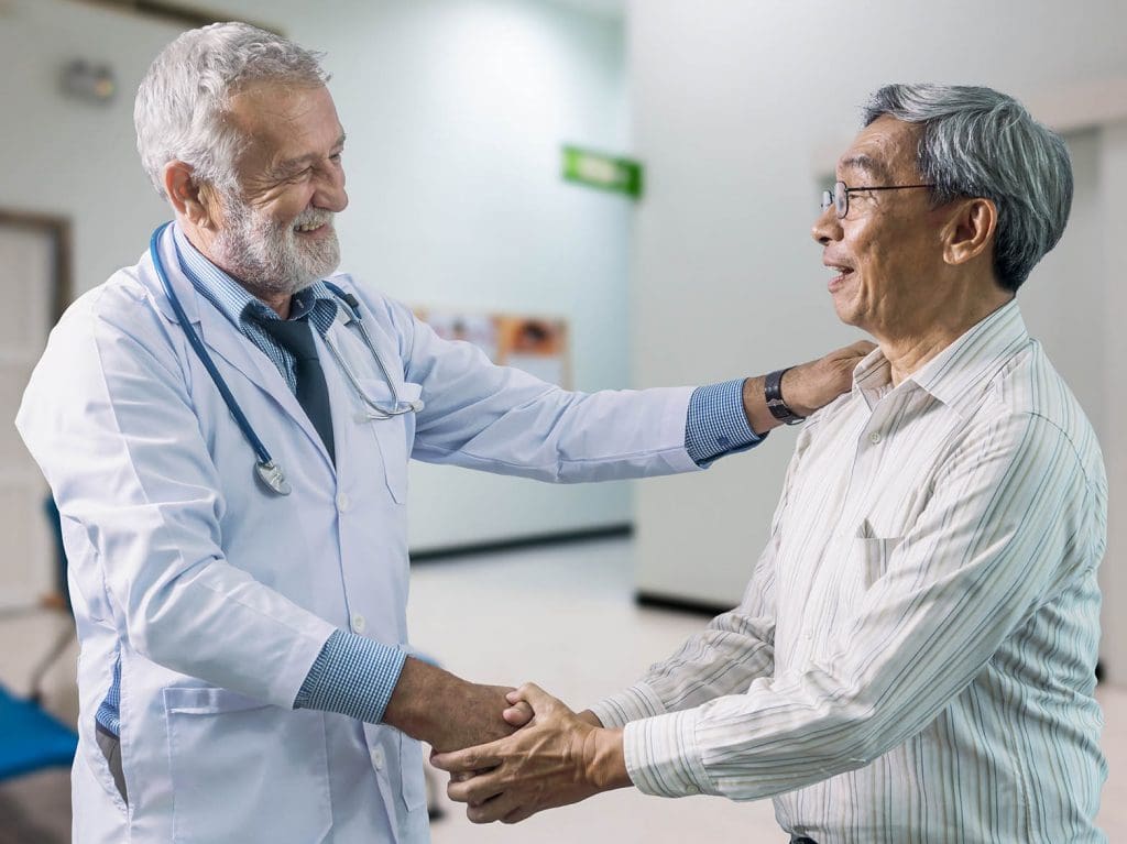 older male doctor shaking the hand of older male patient