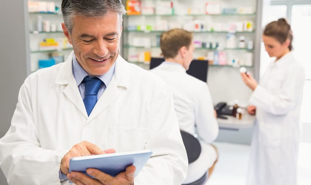 older male pharmacist using a pharmacy billing solution software on a tablet
