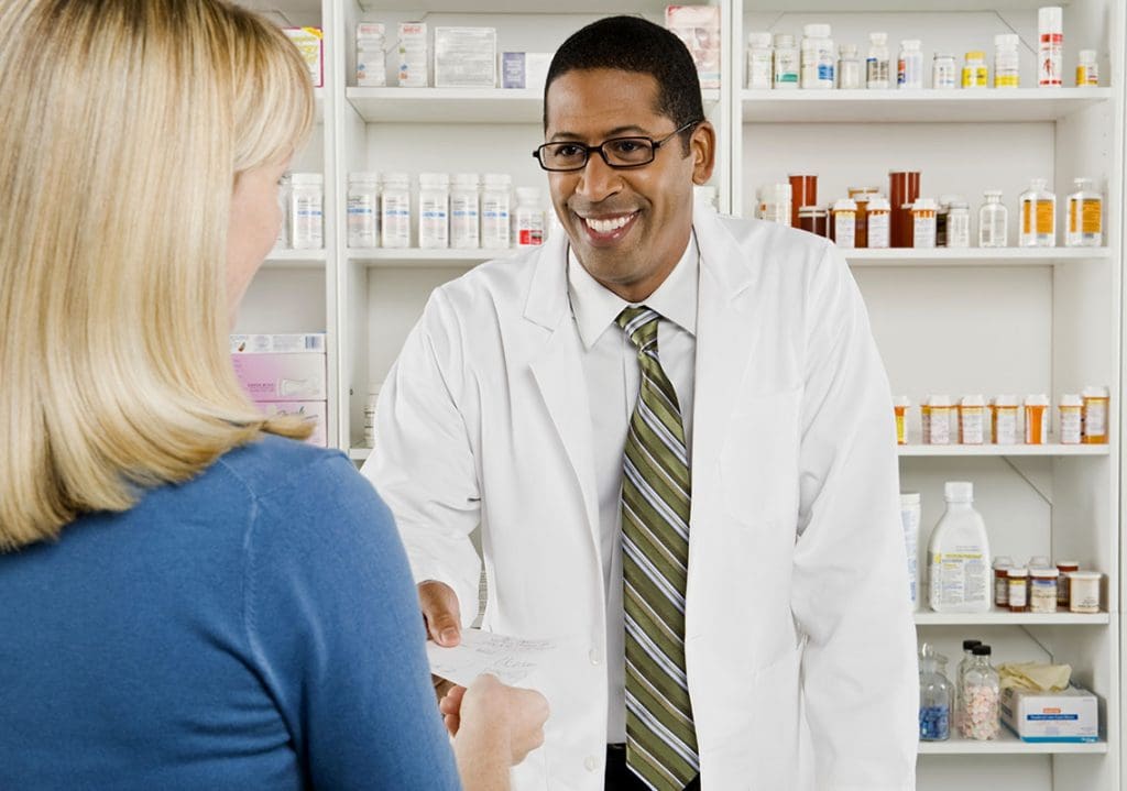Pharmacist handing patient her prescription. 