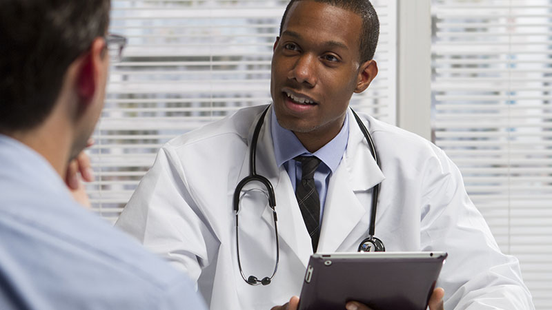 doctor holding tablet speaking with patient