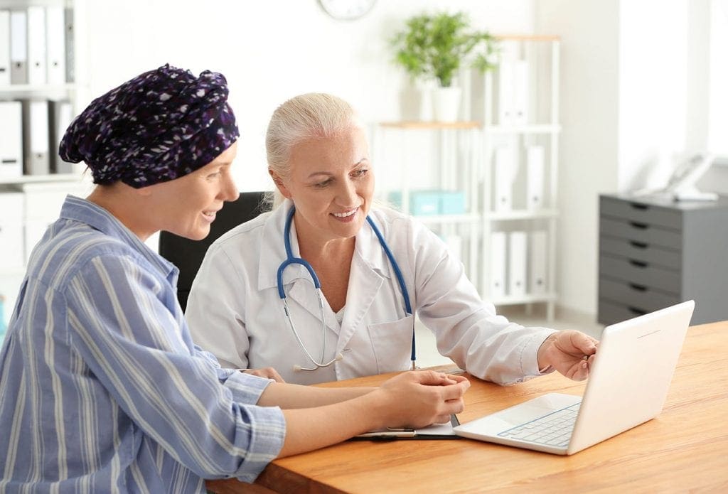 older female doctor and female patient looking at electronic health record on laptop
