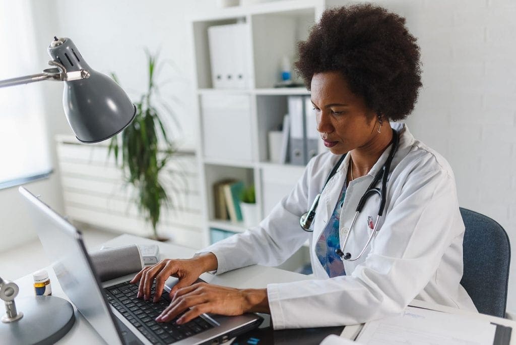 female doctor typing at her desk on a laptop electronic health record